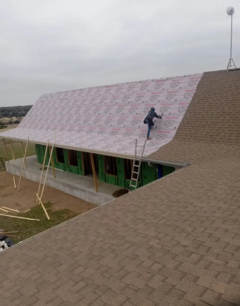 Worker preparing underlayment for a metal roof installation in Beaver Falls